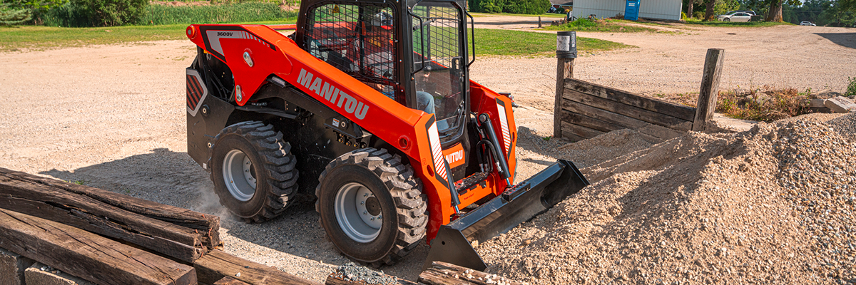 red skid steer picking up dirt