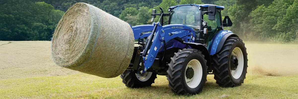blue tractor carrying haybale